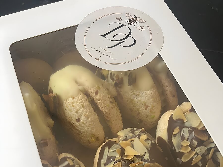 Witte doos met venster vol minibokkepoten, dichtgeplakt met het ronde DP Pâtisserie-zegel