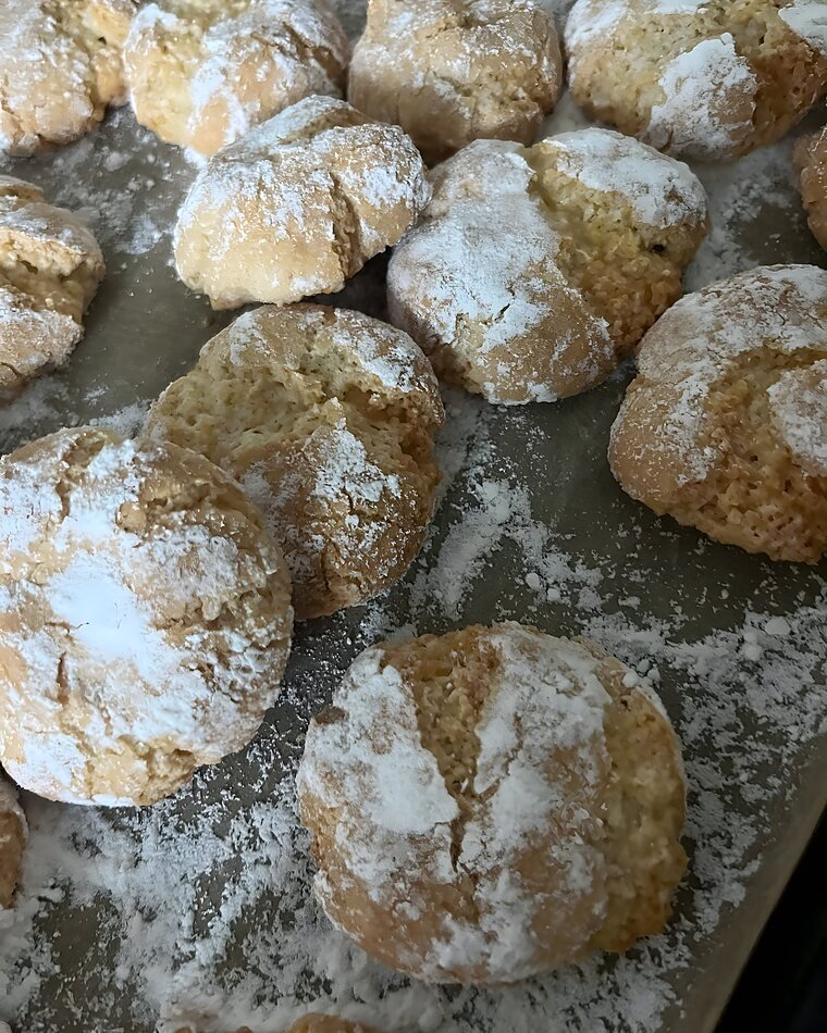 Amaretti met poedersuiker, opengebarsten, op een bakplaat