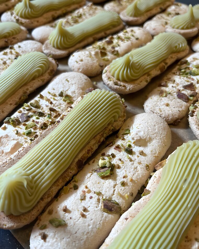 Pistachecrème wordt met een getande spuitmond op de bokkepoten gespoten